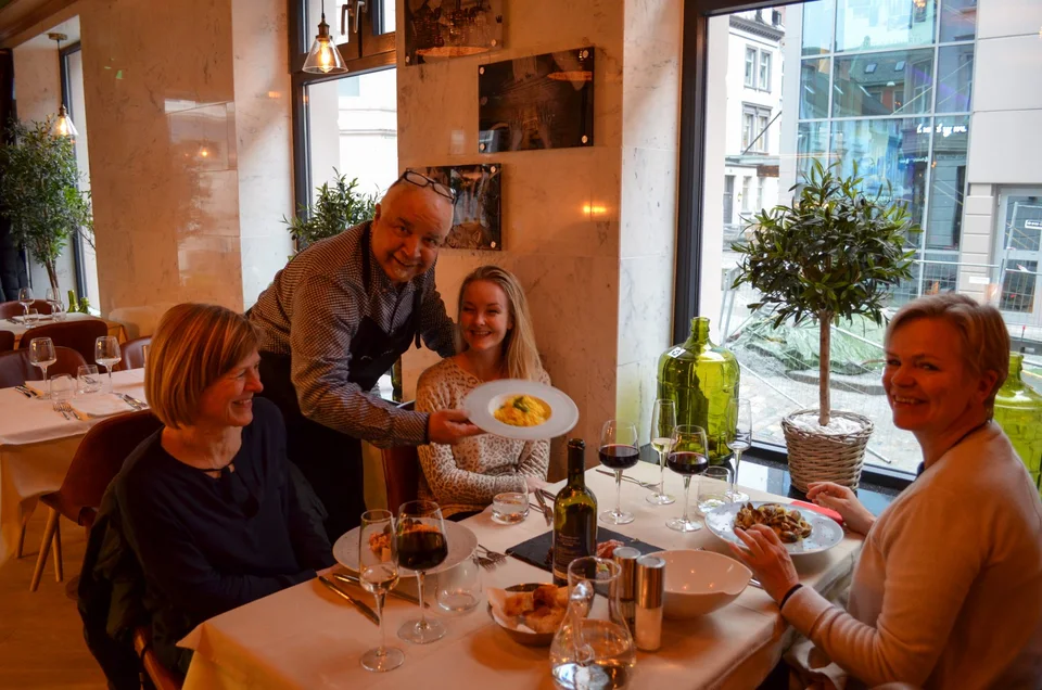 En vert serverer gjester ved et vindusbord hos Amici Miei