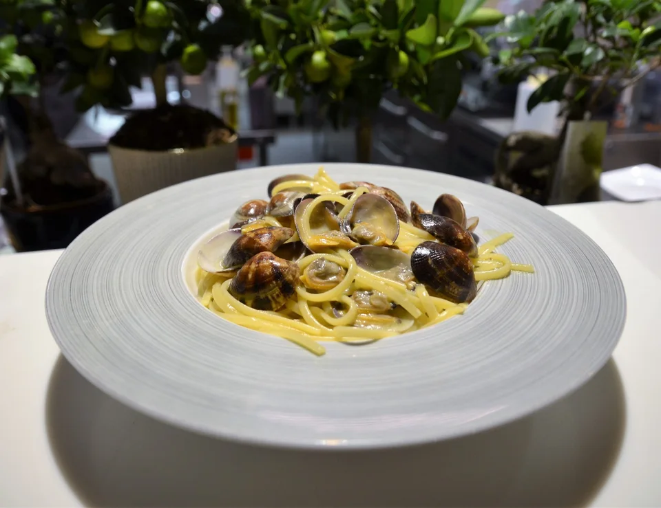 Pasta med skjell på en hvit tallerken ved restaurantens vindu